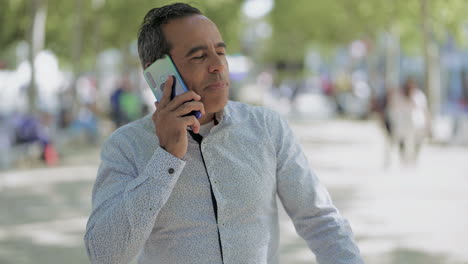 Man-talking-by-cell-phone-and-walking-on-street