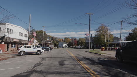 Wilson,-NY,-USA,-October-2021:-Mashana-drives-through-the-central-street-of-a-small-American-town.-Shop-buildings,-road-signs-and-houses-are-visible