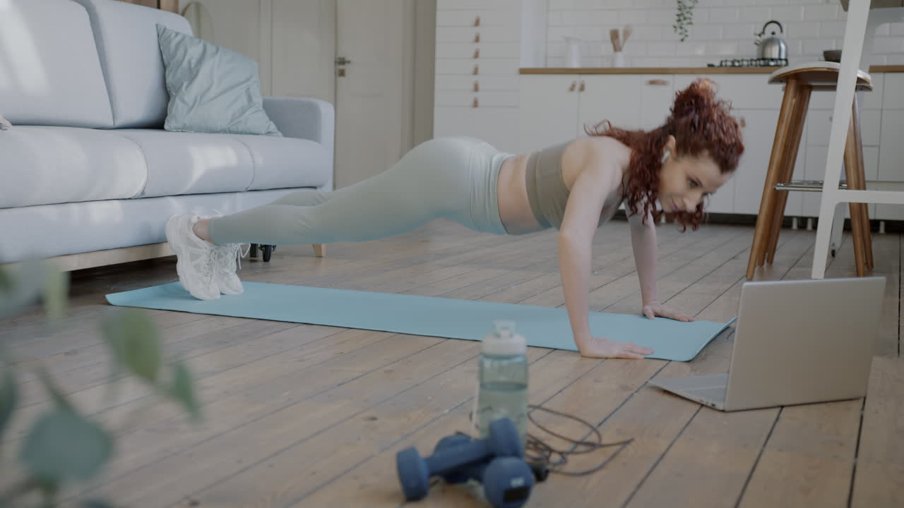 Woman doing push-ups at home using an online fitness video