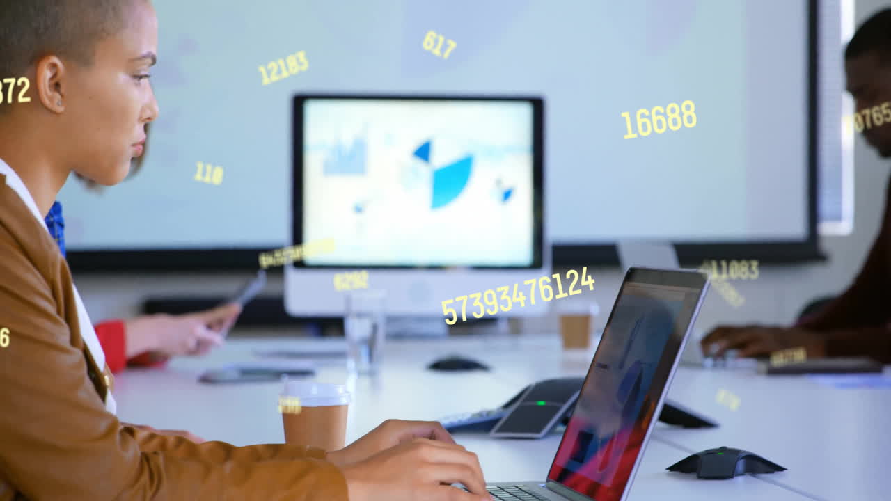 animación del procesamiento de datos sobre una mujer de negocios biracial que usa una computadora portátil en la oficina
