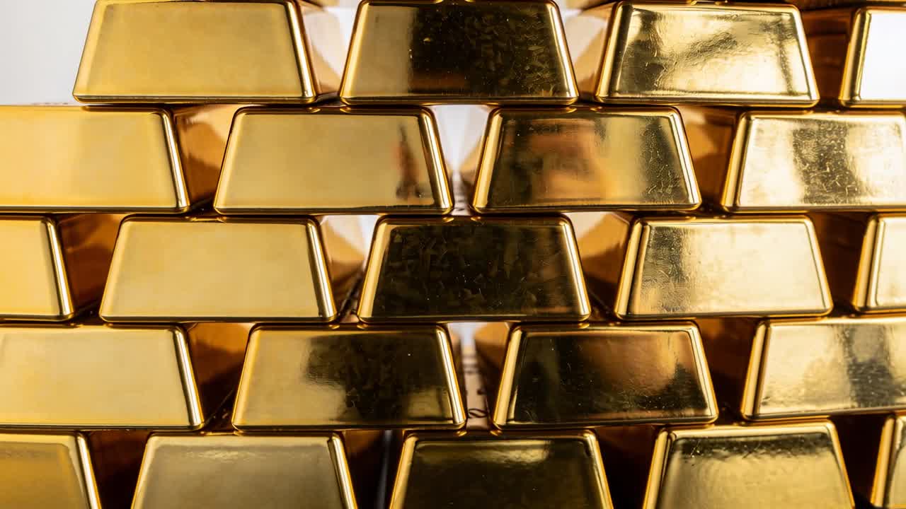 Video verticale: Telecamera che si sposta rivelando un riflesso sfocato dietro lingotti d'oro impilati in uno studio.