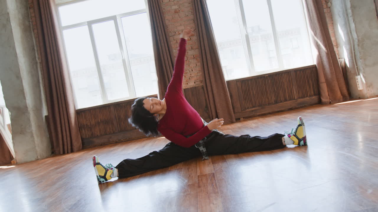 Young woman performing side splits and stretching in a dance studio