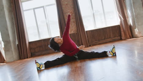 young woman performing side splits and stretching in a dance studio