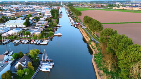 canal view with boats, nl. quiet canal lined with boats and trees under a clear sky near urban areas in the netherlands during daylight
