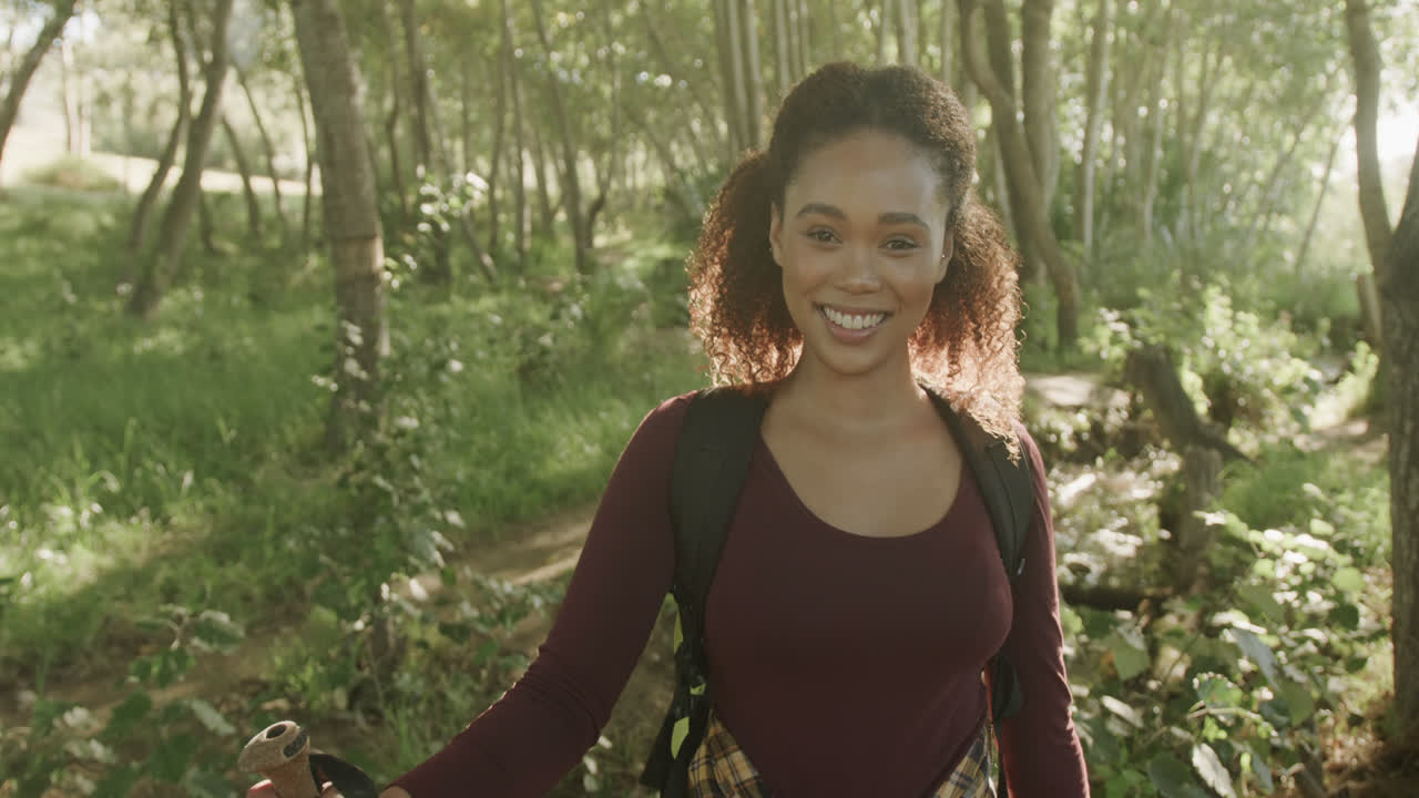 retrato de una feliz mujer afroamericana caminando en el bosque, en cámara lenta