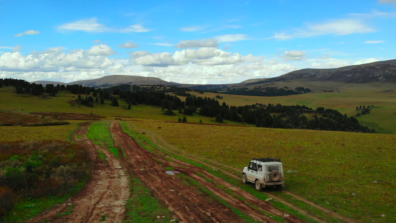 SUV driving on a dirt road through a mountainous landscape