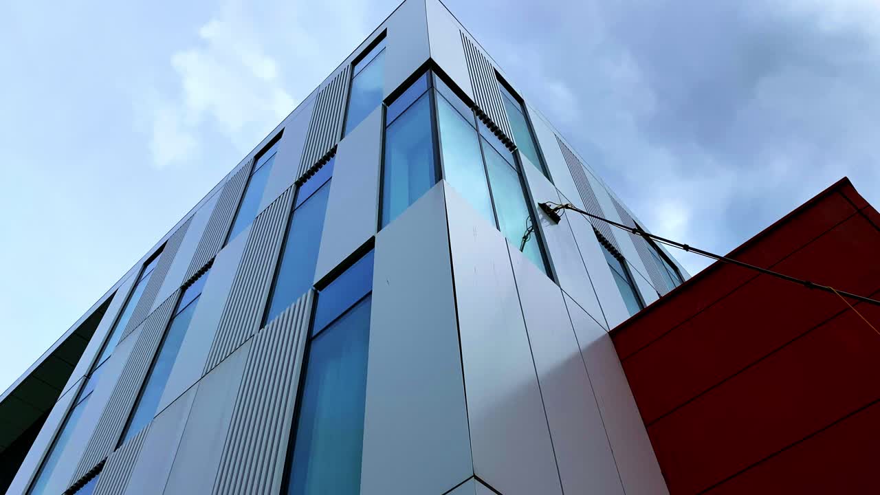 Static footage of the exterior of building being mopped and cleaned with a long mop handle. View from below