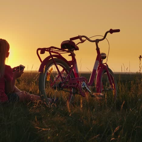 a child sits on the bike admiring the sunset