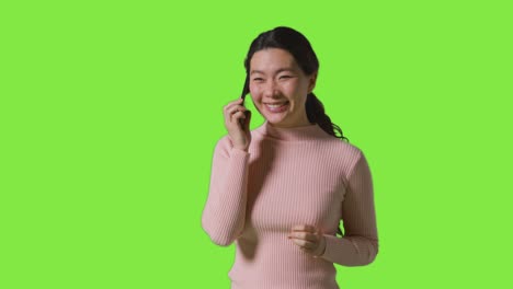 Studio-Shot-Of-Woman-Talking-On-Mobile-Phone-And-Getting-Good-News-Against-Green-Screen