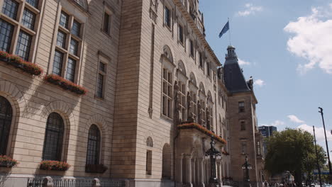 Tilting-shot-of-the-stunning-Rotterdam-town-hall,-sandstone-building-flying-the-Dutch-and-EU-flags