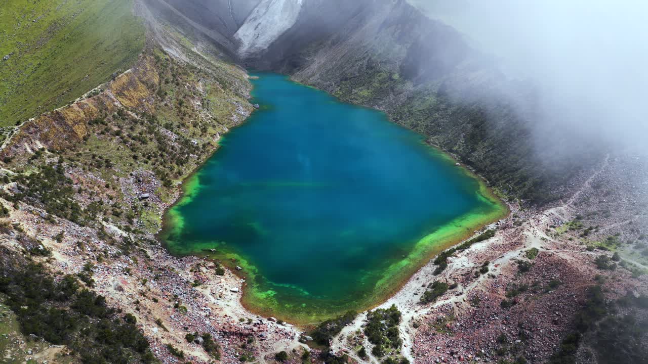 Torquise Laguna Lake Humantay glacier snow capped Humantay trek Peru aerial drone birdseye view rainy season sunny fog clouds high altitude hiking Cusco Peruvian Andes range morning circle left