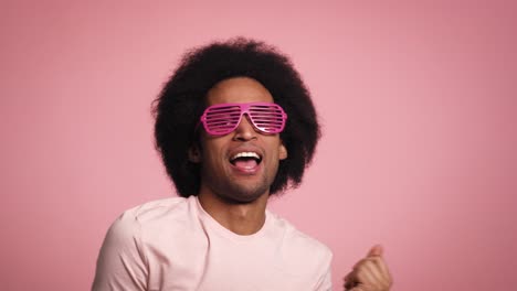 young african man smiling and dancing in the pink glasses