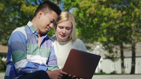 couple using laptop outdoors