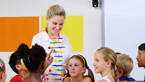 teacher assisting school kids in learning abacus in classroom