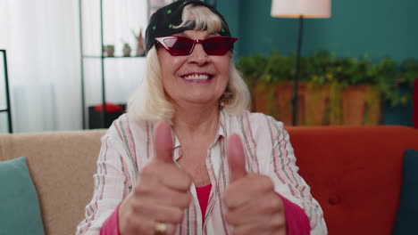 Grandmother-old-woman-looking-at-camera-raises-thumbs-up-agrees-with-something-positive-good-at-home