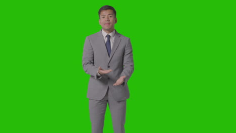 three quarter length shot of angry businessman in suit against green screen talking to camera