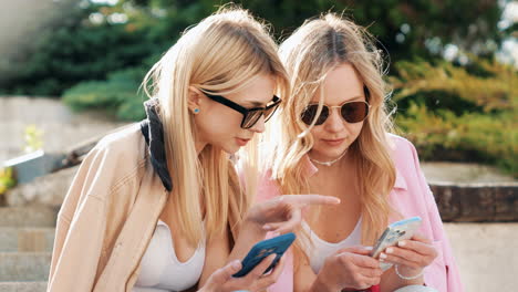 two young women using smartphones outdoors