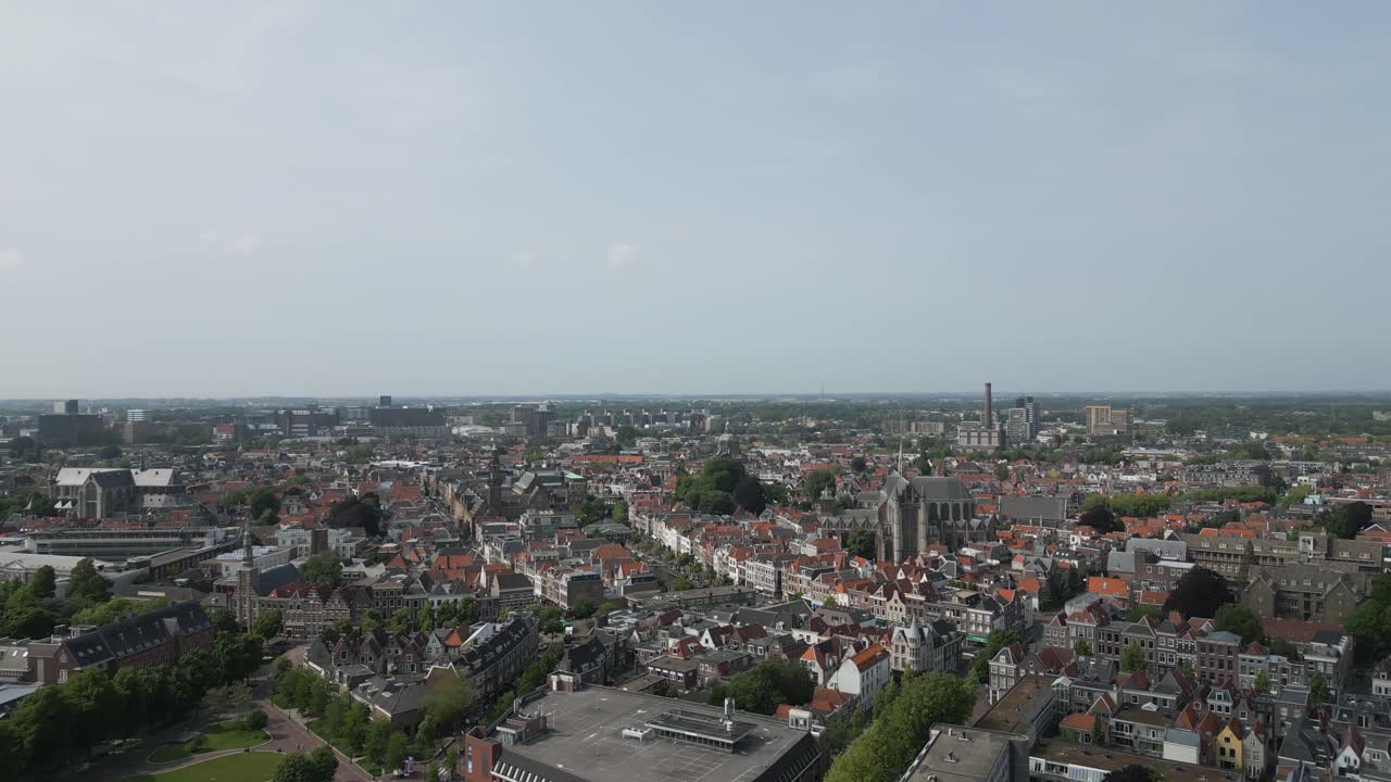 Drone footage of the traditional dutch city of Leiden with red-tiled roofs, churches and dense architecture on a clear day.