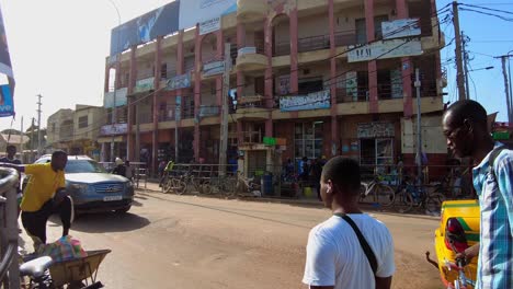 busy street intersection at serekunda market with vendors, pedestrians, and passing vehicles