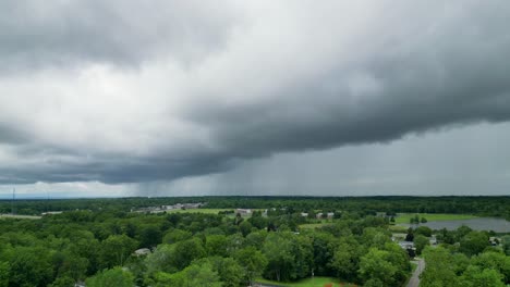 drone shot of ominous storm clouds rolling over a suburban area with lush greenery below