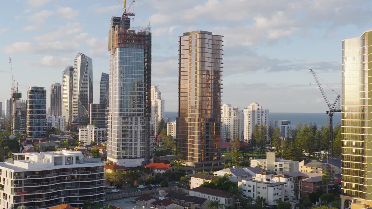 Drone footage captures Gold Coast's skyline with skyscrapers and ocean backdrop during golden hour, highlighting urban development and coastal beauty