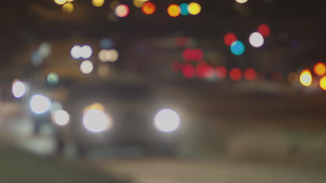 defocused traffic drives past street level camera at night