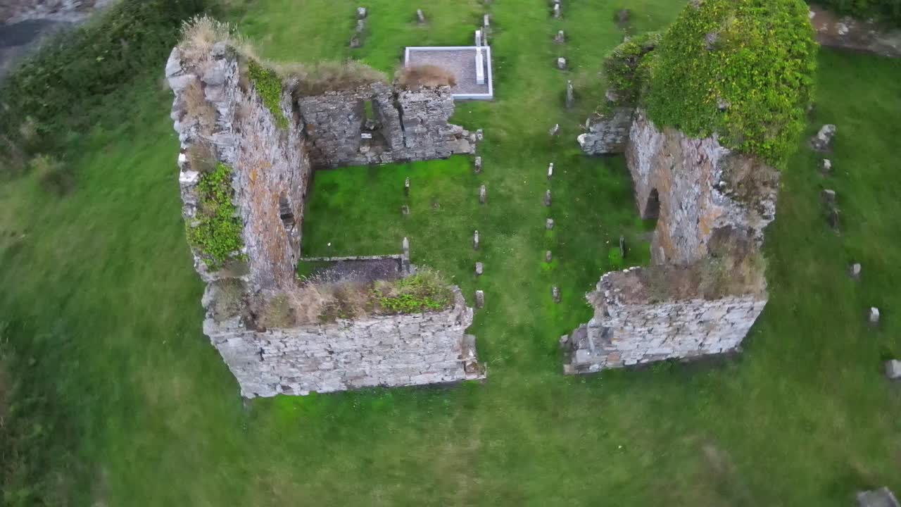ruina de una antigua iglesia de piedra con tumbas por dentro y por fuera en irlanda