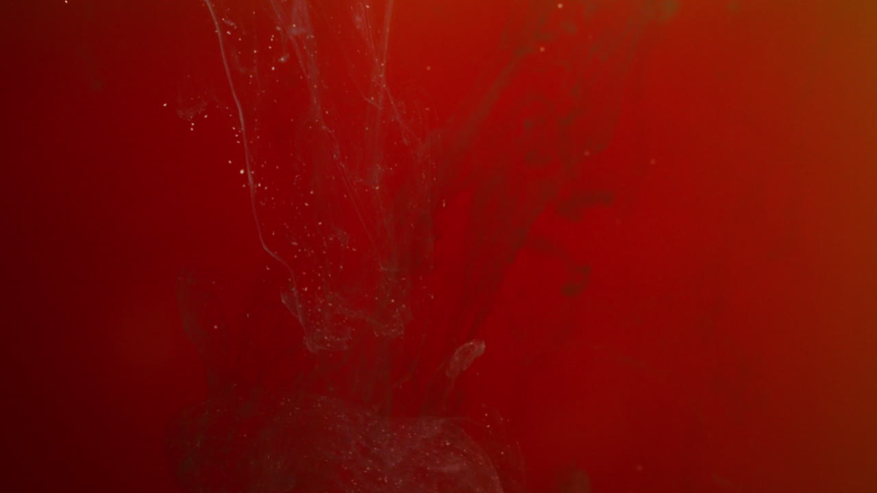 오렌지색과 빨간색의 페인트 또는 염료가 색 배경에 물에 떨어지면 회전하는 다채로운 연기 배경을 만니다.