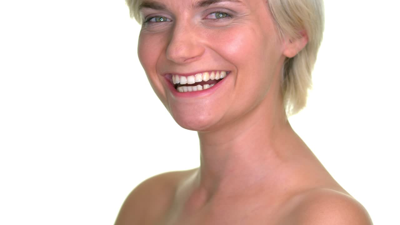 una mujer con el hombro desnudo de pie con una sonrisa pura en su rostro