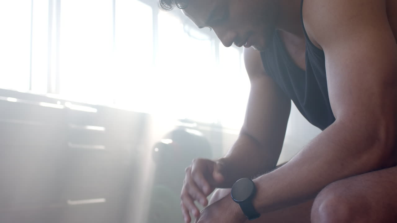 Resting after workout, man in gym wearing smartwatch and gym attire, copy space