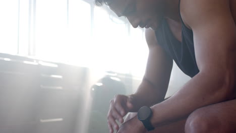 resting after workout, man in gym wearing smartwatch and gym attire, copy space