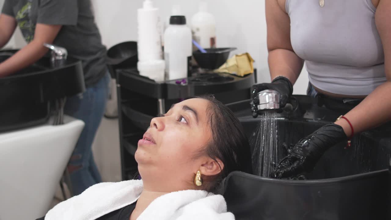 Latina woman enjoying professional hair wash at beauty salon