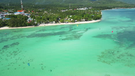 aerial over the turquoise blue waters with kite surfers on ko pha-ngan island, thailand