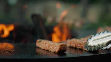 las manos del cocinero usan fórceps para girar la carne afuera. hombre poniendo kebab de carne