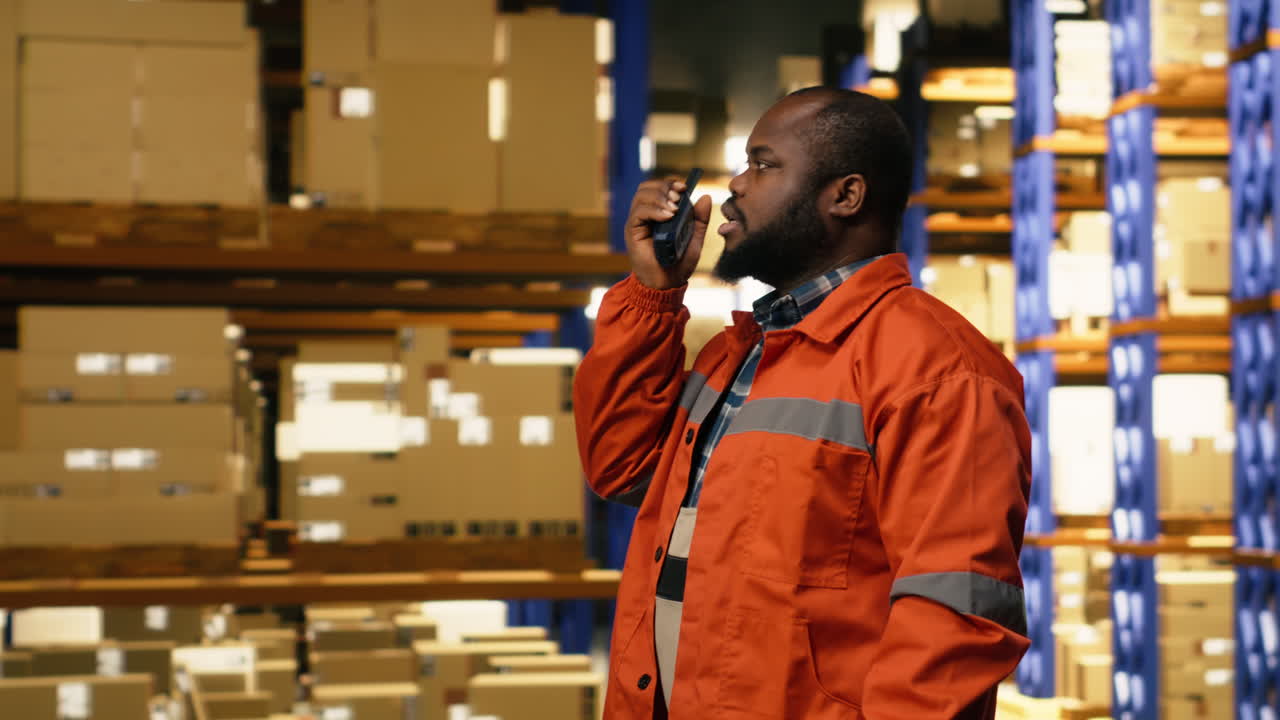 Radio walkie-talkie portatile, in un centro di distribuzione, membro del personale di colore.