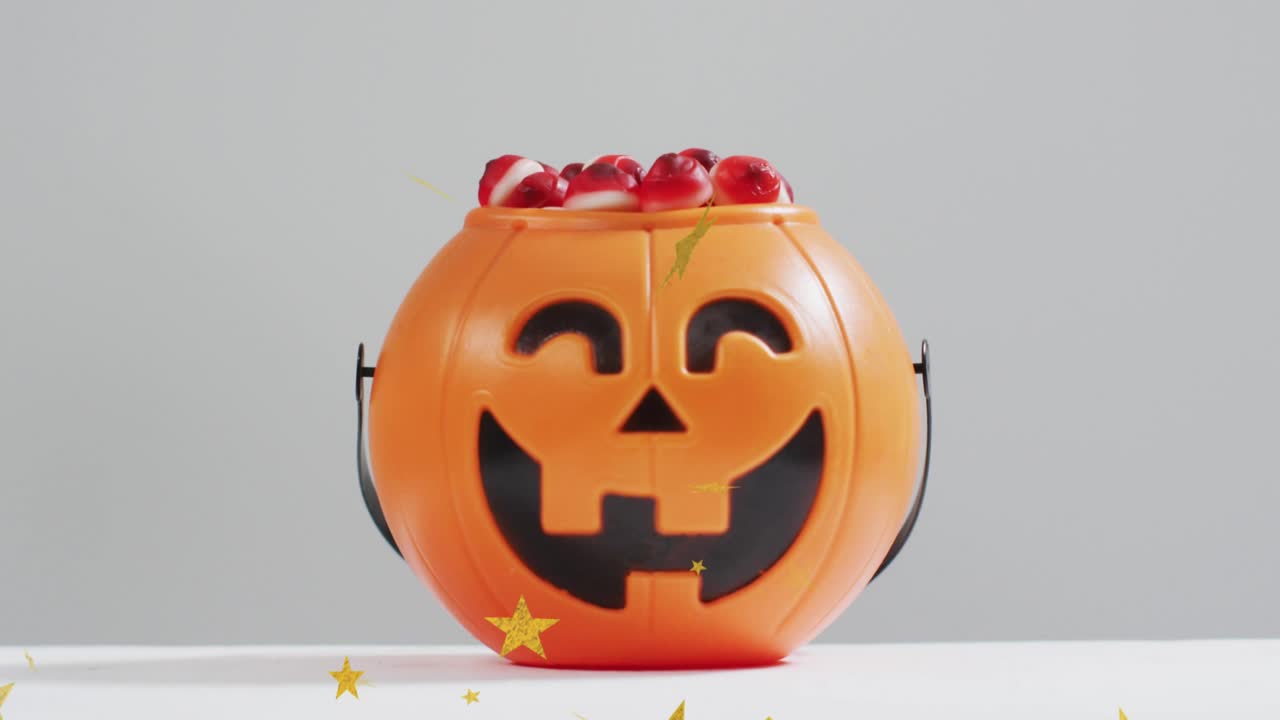 Golden stars drifting inward and scattering around jack-o'-lantern candy bucket, enhancing display
