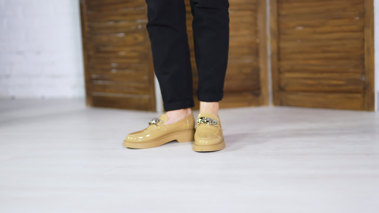 Presentation of beautiful new beige shoes with silver chain decoration. Lady model in black jeans demonstrates footwear. Close up.