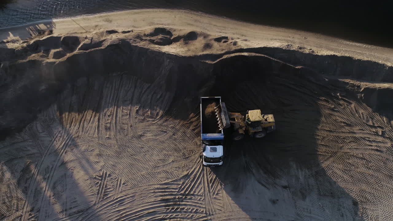 발굴기 와 덤프 트럭 이 모래 를 실고 있는 건설 현장 의 공중 사진