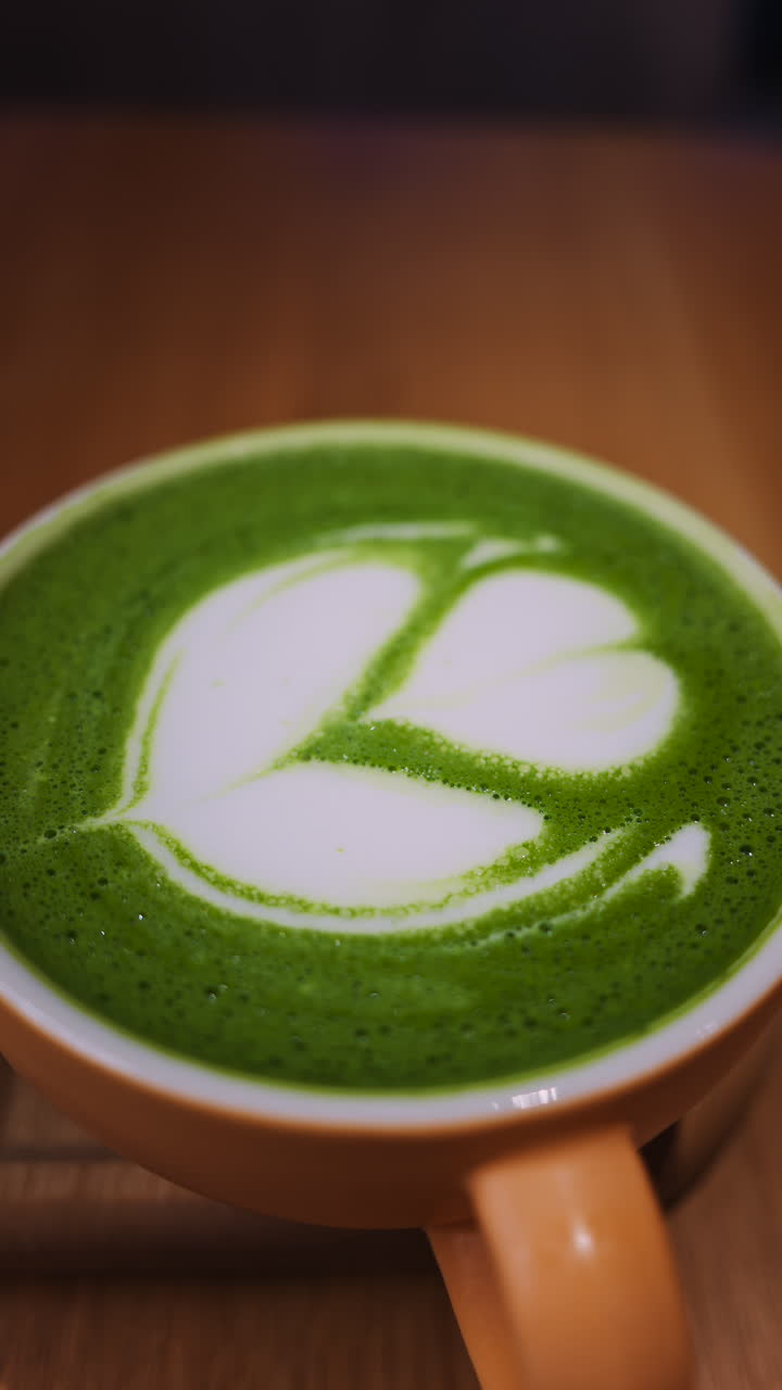 Close up of a matcha latte on a wooden tray at a cafe. Vertical