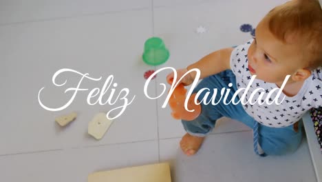 Animation-of-feliz-navidad-text-over-happy-caucasian-baby-at-christmas