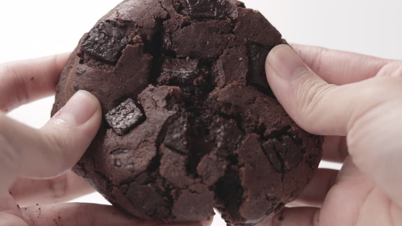 Double Chocolate Fudge Cookie Split By A Person's Hand