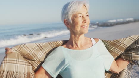 Senior-Caucasian-woman-enjoying-time-at-the-beach-with-sea-in-the-background