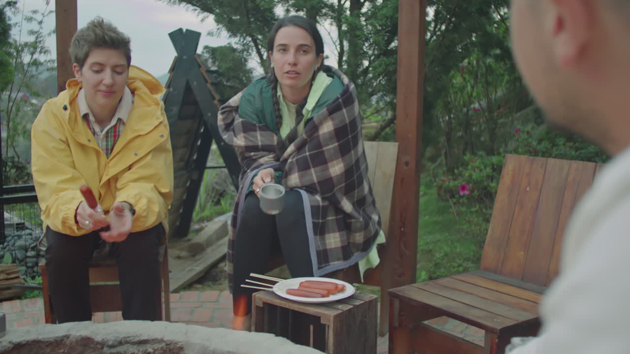 Young Women Speaking with Friend by Campfire