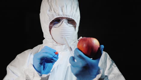 a man in protective clothing and gloves takes a smear from a large apple 4