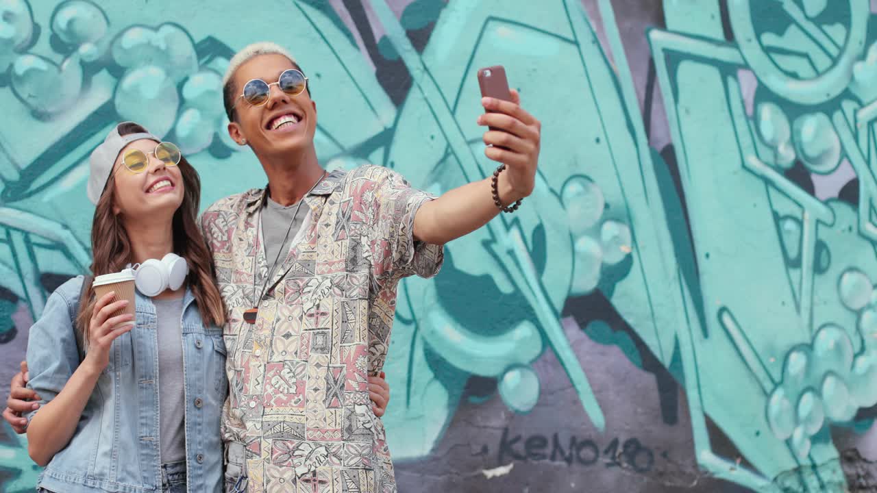 pareja divertida hipster con ropa elegante haciendo un selfie con un smartphone en la calle