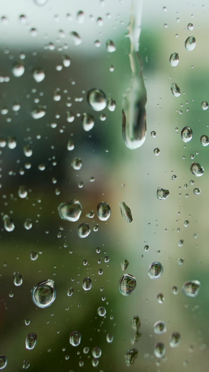 Water texture on glass. Rain drops on window glass. Rainy background. Abstract raindrop scenery background. Close-up. Vertical video