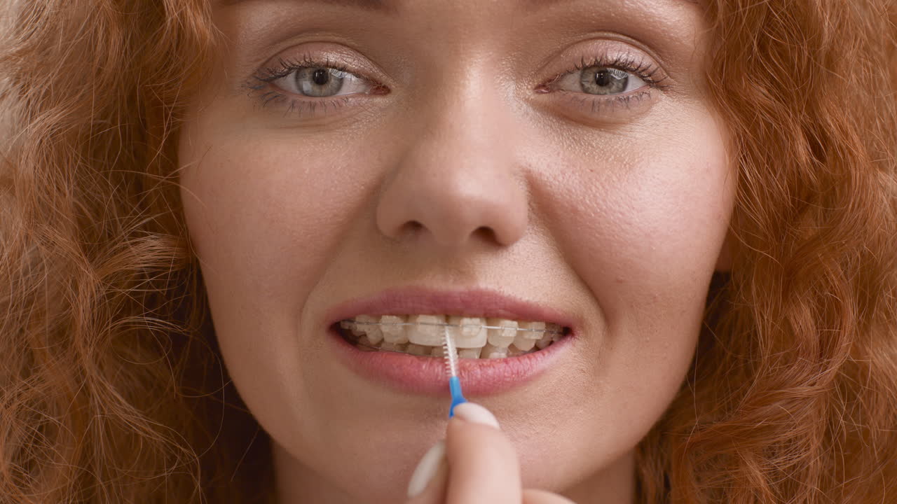 Close-up of a woman cleaning her dental braces with an interdental brush