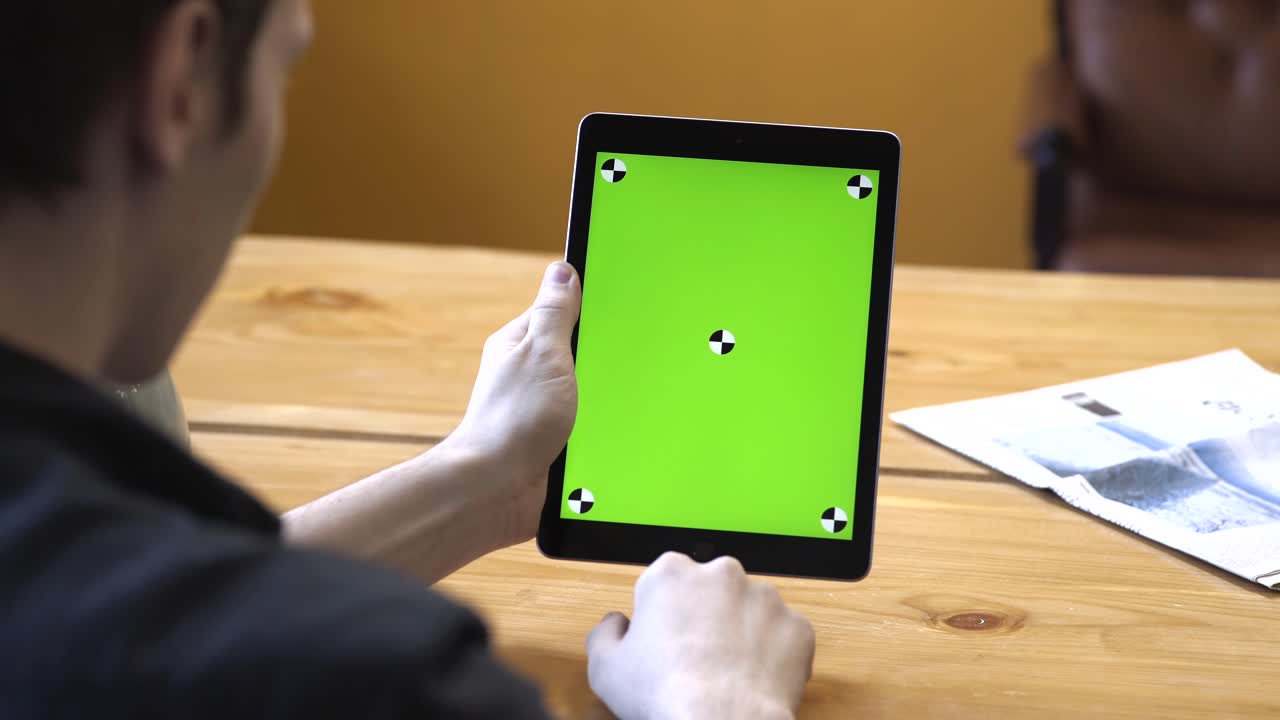 녹색 화면을 가진 태블릿을 사용하는 사람