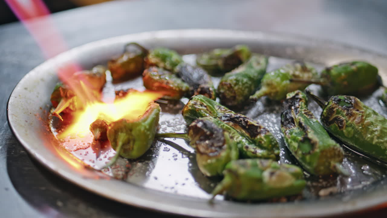 Closeup fiery peppers grilled with flames in kitchen. Green jalapeno roasting