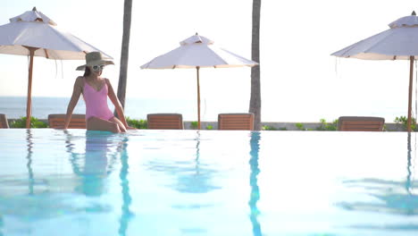 Sitting-at-the-far-end-of-a-resort-swimming-pool-with-an-ocean-view-in-the-background